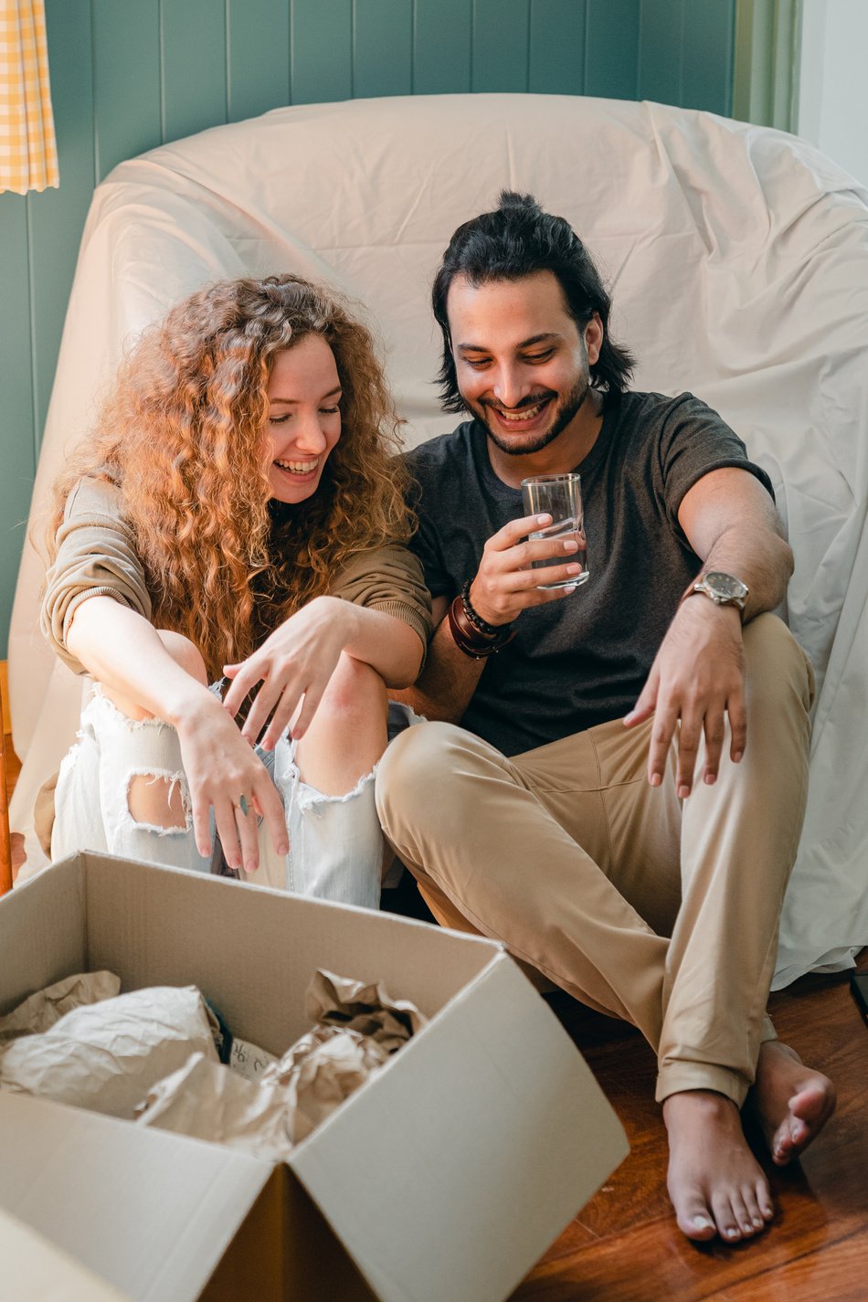 Cheerful diverse couple sitting on cozy couch while moving